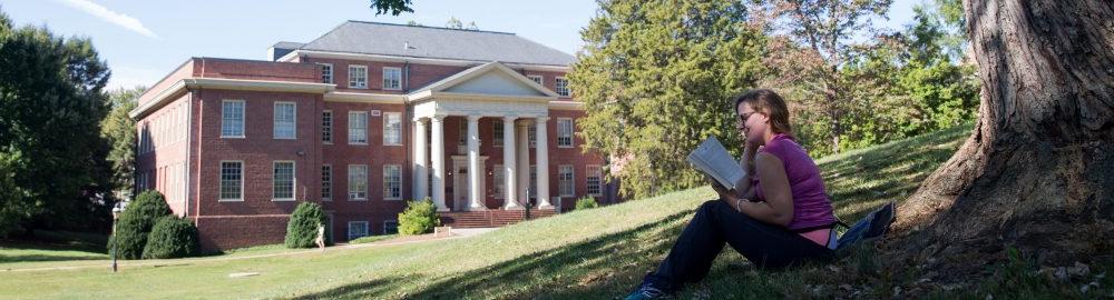 Photo of student reading a book on campus