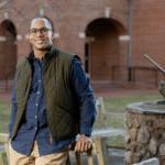 Carl Coffey poses in front of a bench on campus.